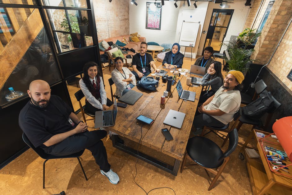 A group of diverse professionals collaborating in a modern office setting with laptops and technology