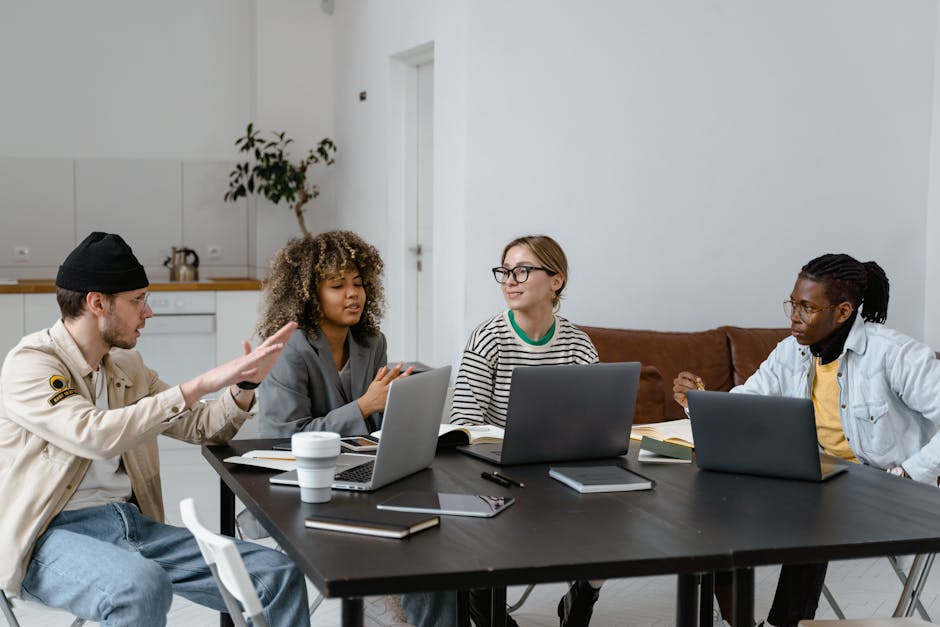Group of diverse colleagues collaborating with laptops in a modern office setting