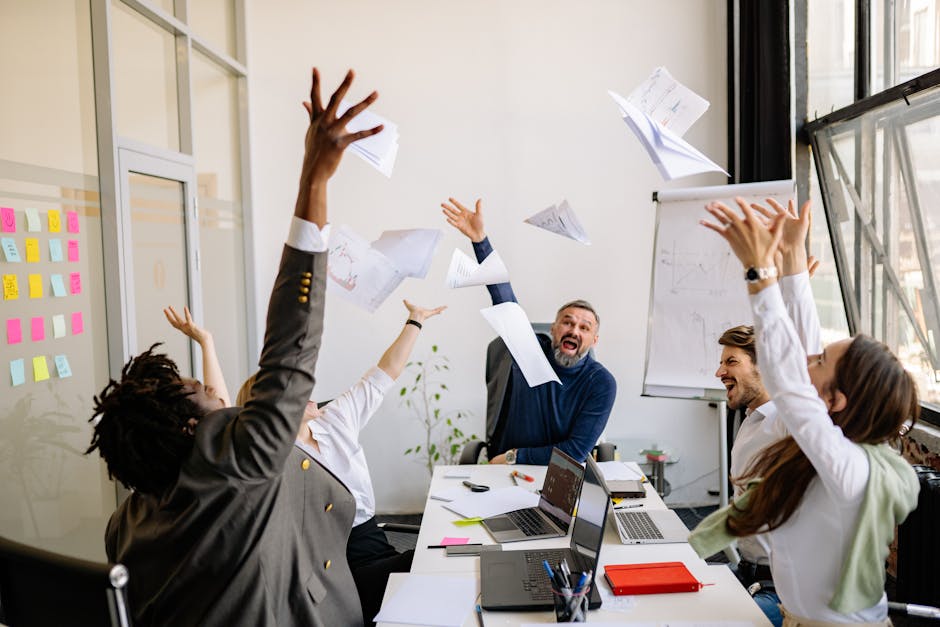 A diverse office team celebrating with papers in the air, showing teamwork and success