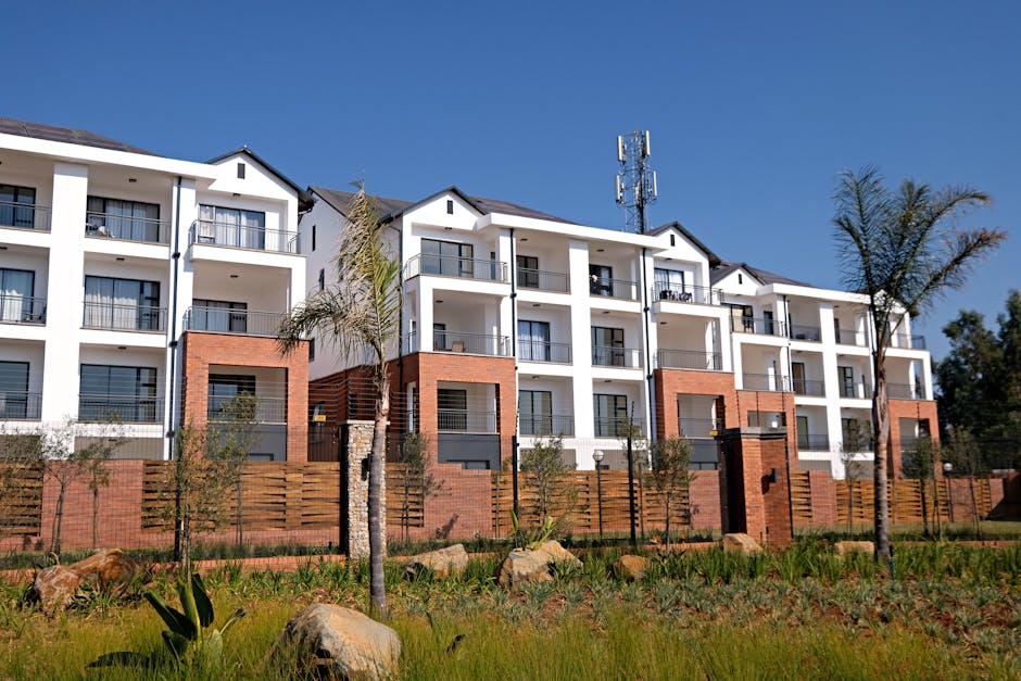 Contemporary apartment complex with garden, featuring white facade and red brick accents.
